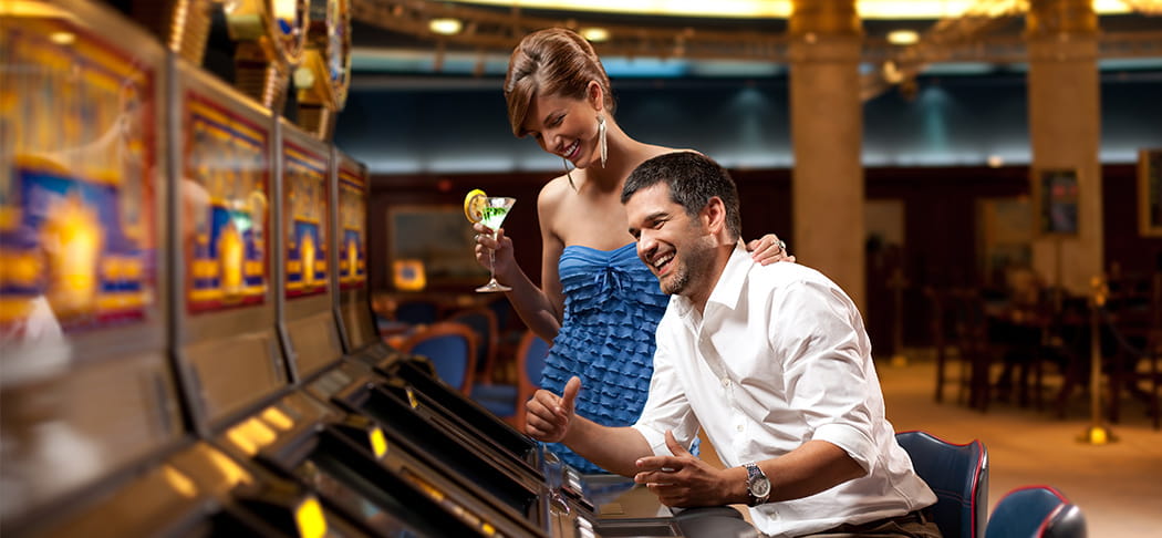 A man and woman play a slot machine.