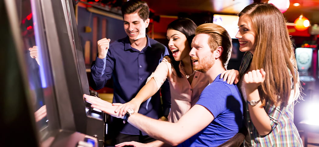 A group of friends play a slot machine.