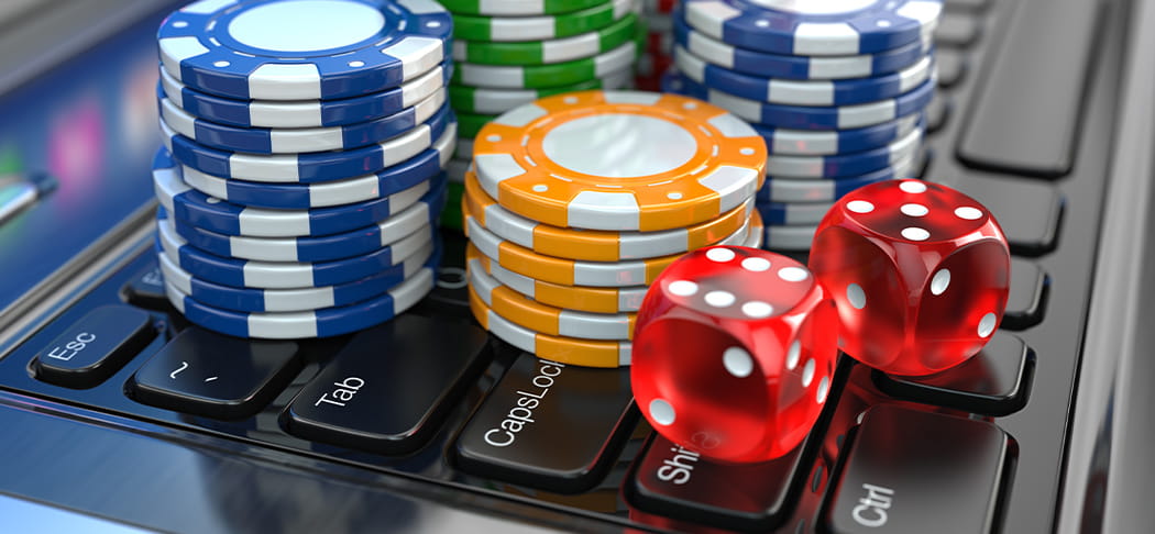 Poker chips and dice on top of a laptop.