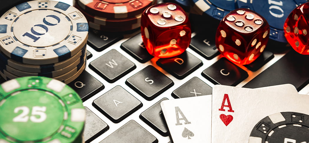 Casino dice and cards on top of a computer.