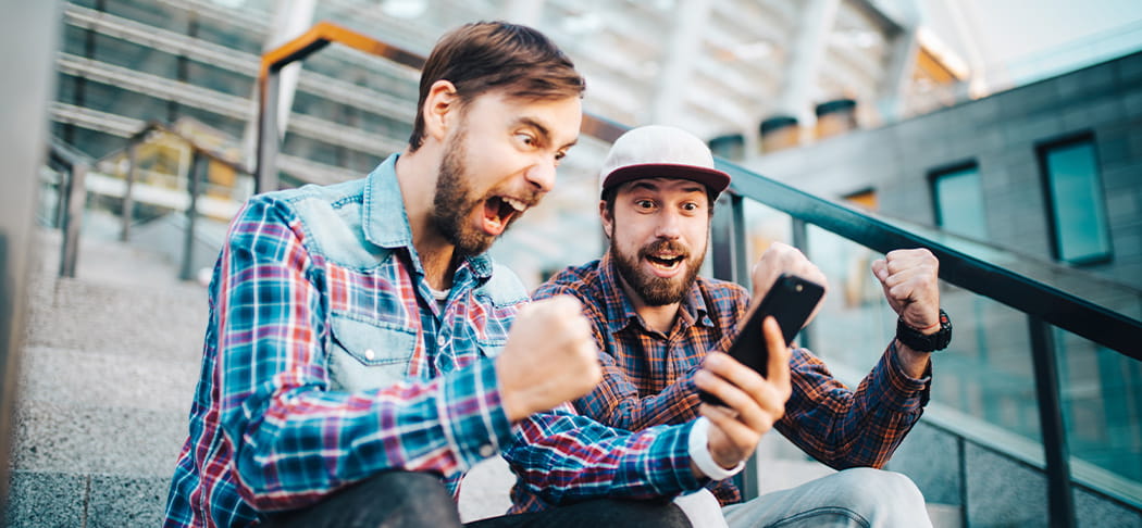 Two guys watch sports on a phone.