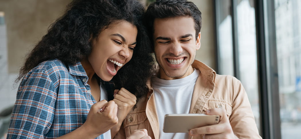 A man and woman watch sports on a phone.